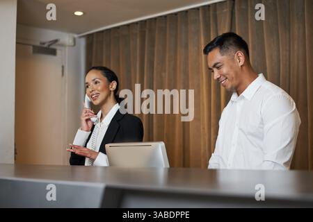Professionelle Rezeptionisten in der modernen Hotellobby empfangen Gäste mit einem herzlichen Empfang Stockfoto