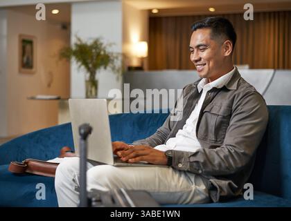 Business Professional mit Laptop in der modernen Lobby-Lounge des Hotels Stockfoto