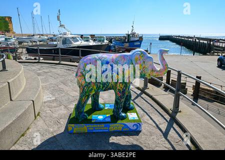 West Bay, Dorset, Großbritannien. April 2025. Wetter in Großbritannien. Eine farbenfroh bemalte Elefantenskulptur, die Teil des Kunstwegs Stampede by the Sea in West Bay in Dorset ist, an einem Tag mit heißem Frühlingssonne und klarem blauem Himmel . Bildnachweis: Graham Hunt/Alamy Live News Stockfoto