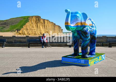 West Bay, Dorset, Großbritannien. April 2025. Wetter in Großbritannien. Eine farbenfroh bemalte Elefantenskulptur, die Teil des Kunstwegs Stampede by the Sea in West Bay in Dorset ist, an einem Tag mit heißem Frühlingssonne und klarem blauem Himmel . Bildnachweis: Graham Hunt/Alamy Live News Stockfoto