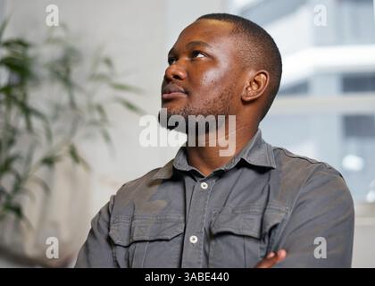 Nachdenklicher junger Mann, der in einer Innenumgebung aufblickt und Ideen erwägt Stockfoto