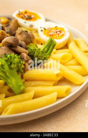 Leckeres Frühstück, Pasta mit gebratenen Pilzen und Brokkoli, grüne Erbsen und Mais, frischer Salat mit Radieschen mit Samen Stockfoto