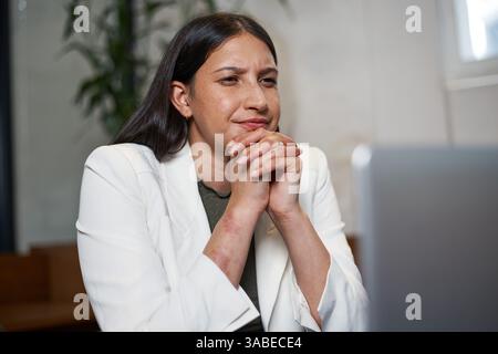 Professionelle Frau in Geschäftskleidung, die sich in virtuellem Meeting in einem modernen Büroumfeld engagiert Stockfoto