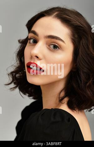 Eine schöne junge Frau zeigt ihre roten Lippen und Zahnspangen und strahlt Selbstvertrauen und Charme aus. Stockfoto