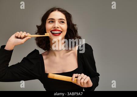 Die junge Frau zeigt ein wunderschönes Lächeln mit Zahnspangen, während sie eine Bambuszahnbürste glücklich hält. Stockfoto