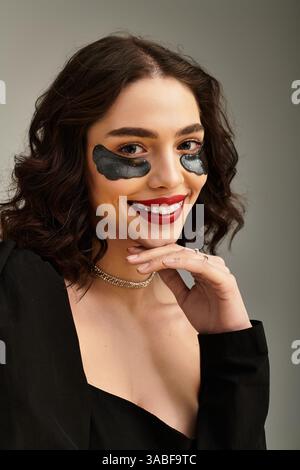 Eine auffällige junge Frau zeigt ihre roten Lippen und Zahnspangen, während sie lächelt und selbstbewusst posiert. Stockfoto