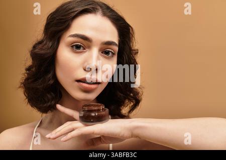 Hübsche junge Frau zeigt ihre Schönheits-Hautpflege-Routine in einer ruhigen Studioatmosphäre. Stockfoto