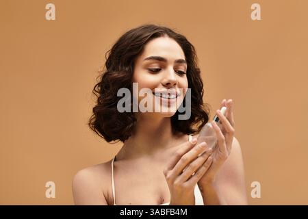 Eine hübsche junge Frau mit Zahnspangen lächelt, als sie ihre Hautpflegeprodukte im Studio präsentiert. Stockfoto