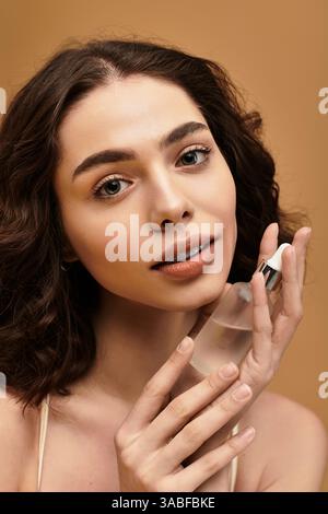 Eine hübsche junge Frau mit Zahnspangen zeigt ihre Hautpflegeroutine in einer lebendigen Studioatmosphäre. Stockfoto