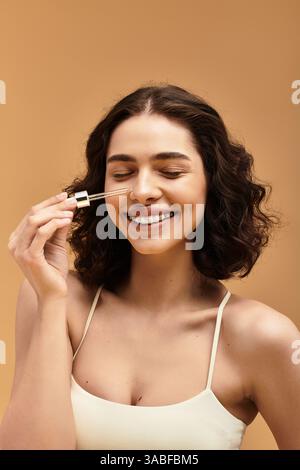 Eine hübsche junge Frau zeigt ihre Schönheitsroutine in einem Studio, während sie selbstbewusst lächelt. Stockfoto