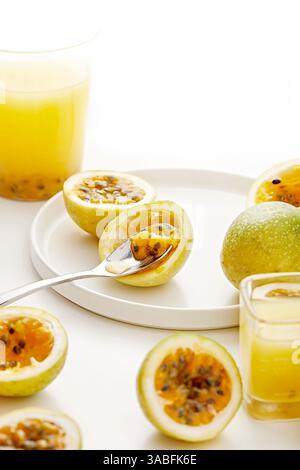 Nahaufnahme frischer Passionsfrucht und Gläser Passionsfruchtgetränk auf einem Tisch Stockfoto