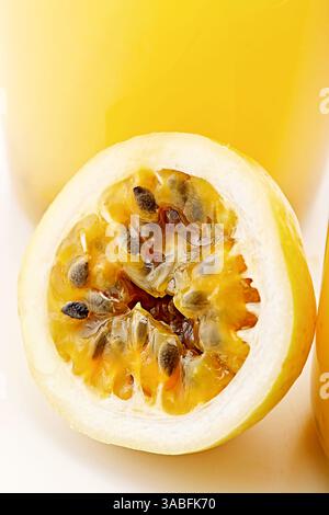 Nahaufnahme einer halben Passionsfrucht vor einem Glas Saft Stockfoto