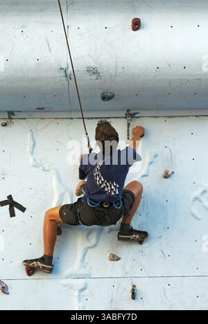 Ein männlicher Freikletterer, der das Klettern auf künstlicher Felswand übt Stockfoto