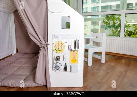 Sensorische Aktivitäts-Platine mit Schlössern, Schaltern und Komponenten, die Kinder über alltägliche Gegenstände informieren und ihnen vermitteln. Interaktives Spielen in einem Safe und Stockfoto