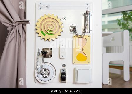 Sensorische Aktivitäts-Platine mit Schlössern, Schaltern und Komponenten, die Kinder über alltägliche Gegenstände informieren und ihnen vermitteln. Interaktives Spielen in einem Safe und Stockfoto