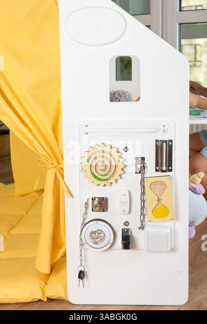 Sensorische Aktivitäts-Platine mit Schlössern, Schaltern und Komponenten, die Kinder über alltägliche Gegenstände informieren und ihnen vermitteln. Interaktives Spielen in einem Safe und Stockfoto