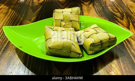 Ketupat oder Reisknödel ist ein traditionelles indonesisches Essen, das auf einem Lebensmittelbehälter serviert wird Stockfoto