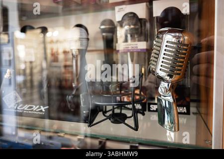 Lemberg, Ukraine - 01. April 2025: Retro-Mikrofone werden hinter Glas in einem Musikgeschäft präsentiert Stockfoto