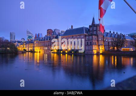 Der Binnenhof leuchtet sanft über den Hofvijver, sein Spiegelbild schimmert im stillen Wasser eines ruhigen niederländischen Abends Stockfoto