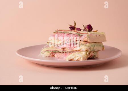 Trendige zarte weiße, rosafarbene Schokolade mit Schicht aus weißem und rosafarbenem Pismaniye auf rosa Hintergrund. Leckeres Dessert. Nahaufnahme. Stockfoto