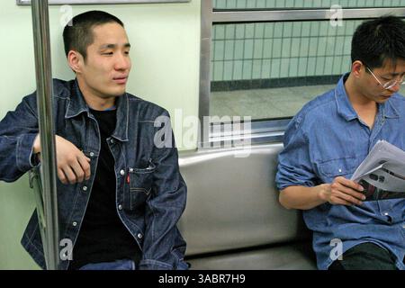 10. April 2005 - Seoul, Südkorea - SHIN HYUN TAK, ein 25-jähriger Fernseh- und Filmschauspieler, liest einem anderen Passagier eine Zeitung über die Schulter, während er mit der U-Bahn in die Innenstadt fährt, um ein Vorsprechen für einen Spielfilm zu machen 10. April 2005 Seoul, Südkorea. Shin Hyun Tak lebt seit seinem 19. Lebensjahr als Schauspieler und trat in vier Fernsehserien und vier Spielfilmen auf. (Kreditbild: © Zoriah/ZUMA Press) Stockfoto