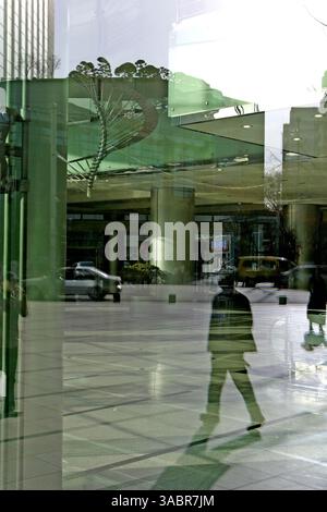 April 2005 – Seoul, Südkorea – Geschäftsleute, die die Straße hinunterlaufen, spiegeln sich in den Fenstern des Nationalen Steueramtes am 10. April 2005 in Seoul, Südkorea. (Kreditbild: © Zoriah/ZUMA Press) Stockfoto