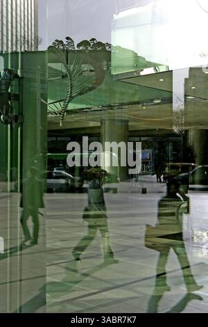 April 2005 – Seoul, Südkorea – Geschäftsleute, die die Straße hinunterlaufen, spiegeln sich in den Fenstern des Nationalen Steueramtes am 10. April 2005 in Seoul, Südkorea. (Kreditbild: © Zoriah/ZUMA Press) Stockfoto