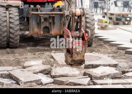 Hydraulischer Schlaghammer am Baggerarm, der bei der Rekonstruktion alter Straßen arbeitet Stockfoto