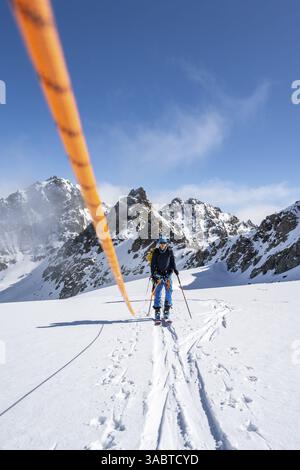Skitourer mit Seil, Seilteam auf dem Gletscher Vadret da Porchabella beim Aufstieg zum Gipfel des Piz Kesch, Berglandschaft im Winter, alpines To Stockfoto