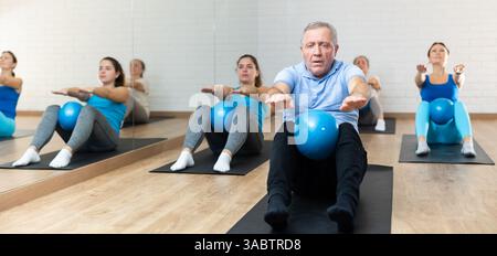 Seniorenmann, der Sit-ups mit Pilates-Ball im Fitnessstudio macht Stockfoto
