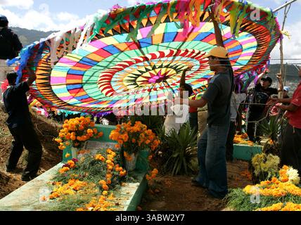 November 2007 - Santiago Sacatepequez, Guatemala - Familien schmücken die Gräber ihrer Angehörigen mit OrangenRingelblumen, Chrysanthemen und wilden Gänseblümchen, aber im Laufe des Festivals werden die Gräber von den Drachenläufern auf dem Friedhof in Santiago Sacatepequez, Guatemala, schwer mit Füßen getreten. Dies ist eine der farbenprächtigsten Traditionen Guatemalas, wo die Einheimischen riesige Drachen fliegen, etwa 15 Meter breit, um mit ihren verstorbenen Lieben zu kommunizieren. Die Riesendrachen haben kleine Botschaften, die an ihre Schwänze gebunden sind, in denen die VI Stockfoto