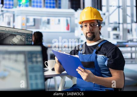 Porträt eines Ingenieurs in der Photovoltaik-Fabrik, der Papiere zur Diagnose von Systemfehlern überprüft. Mitarbeiter der Solaranlage lesen Inspektionsdaten, um Ausfallzeiten zu reduzieren Stockfoto