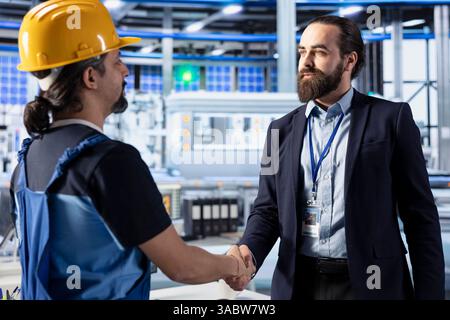 Betriebsleiter und Ingenieur der Photovoltaik schütteln die Hand und erzielen eine Einigung über die Erzeugung nachhaltiger grüner Energie. Geschäftsmann in Solarpaneelen schließt Partnerschaft mit Handshake ab Stockfoto