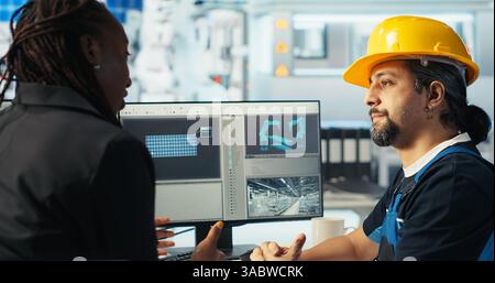 Arbeiter in der Photovoltaik-Fabrik diskutiert mit Frau über die Systemleistung. Produktionsanlage für Solarpaneele afroamerikanischer Manager im Gespräch mit Ingenieur über Energieerzeugung, Kamera B Stockfoto