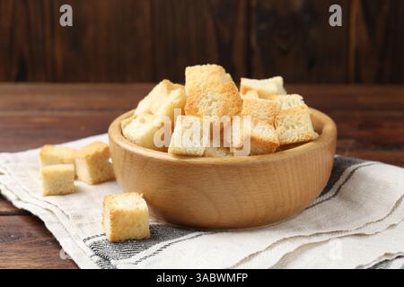 Leckere knusprige Croutons in Schüssel auf Holztisch, Nahaufnahme Stockfoto