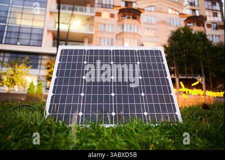 Photovoltaik-Sonnenkollektor vor einem modernen Apartmentgebäude mit Balkonen, die auf eine Wohn- oder Mischnutzung schließen lassen. Konzept der Integration nachhaltiger erneuerbarer Energiequellen in die Architektur. Stockfoto