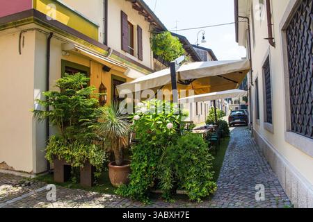 Eine kleine Bar mit überdachtem Außenbereich und viel Grün im historischen Zentrum von Udine, Friaul-Julisch Venetien, Nordost-Italien. Stockfoto