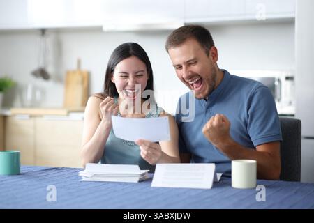 Aufgeregt interrassisches Paar liest gute Nachrichten in der Küche zu Hause Stockfoto