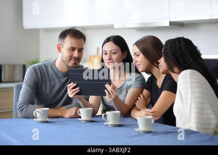 Interrassische Gruppe von Freunden, die in einer Küche zu Hause ein Tablet überprüfen Stockfoto
