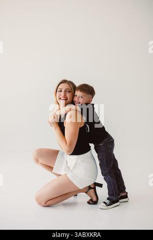 Ein herzlicher Moment in einem gemütlichen Studio fängt die Liebe der Mutter und die spielerische Interaktion mit ihrem Sohn ein und unterstreicht die freudige Bindung, die mit Wärme und Wärme erfüllt ist Stockfoto