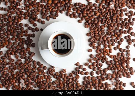 Blick von oben auf eine dampfende Tasse schwarzen Espresso in einer weißen Tasse, umgeben von gerösteten Bohnen auf einer sauberen Oberfläche, die Wärme weckt, Morgenrituale, A Stockfoto