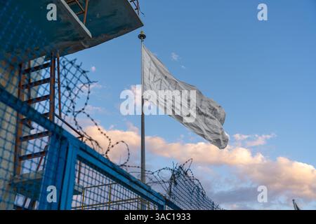 Die Nationalflagge Afghanistans hinter einem Metallzaun und Stacheldraht Stockfoto