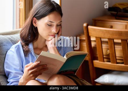 35-jährige Frau zu Hause, liest ein Buch Stockfoto
