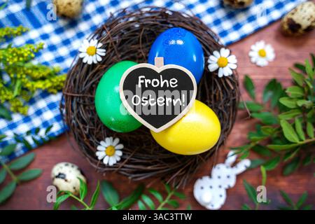 Bayern, Deutschland - 2. April 2025: FOTOMONTAGE, Happy Easter Greeting in einem liebevollen Herzschild mit Osternest mit bunten Eiern und Frühlingsdekoration *** FOTOMONTAGE, Frohe Ostern Gruß im liebevollen Herzschild mit einem Osternest mit bunten Eiern und frühlingshafter Dekoration Stockfoto