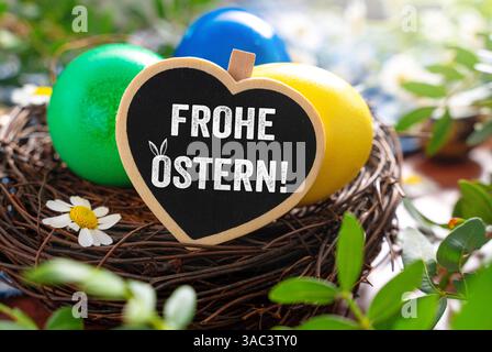 Bayern, Deutschland - 2. April 2025: FOTOMONTAGE, Happy Easter Greeting in einem liebevollen Herzschild mit Osternest mit bunten Eiern und Frühlingsdekoration *** FOTOMONTAGE, Frohe Ostern Gruß im liebevollen Herzschild mit einem Osternest mit bunten Eiern und frühlingshafter Dekoration Stockfoto