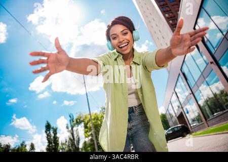 Lächelnde junge Frau mit Kopfhörern genießt Musik an einem sonnigen Tag Stockfoto