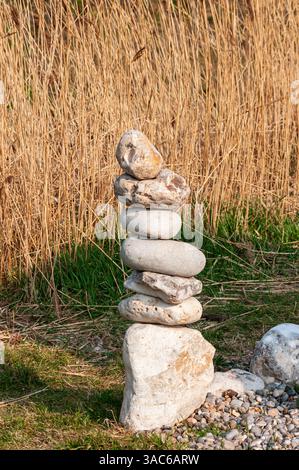 Tower of Balancing Rocks am Strand von Branscombe in East Devon, Großbritannien mit Common Reed dahinter. Teil der englischen Juraküste. Stockfoto