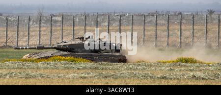 Süd-Israel, Israel. April 2025. Ein israelischer Armeepanzer wirft Staub auf, während er sich im Süden Israels bewegt und am 3. April 2025 in ein vorderes Einsatzgebiet nahe der Grenze zum südlichen Gazastreifen zurückkehrt, das hinter dem Grenzzaun zu sehen ist. Israel hat die Kämpfe im südlichen Gazastreifen verstärkt, da sie die Sicherheitszonen im Gazastreifen vergrößern, um den Druck auf die Hamas zu erhöhen, die seit dem 7. Oktober 2023 inhaftierten israelischen Geiseln freizulassen. Foto von Jim Hollander/UPI Credit: UPI/Alamy Live News Stockfoto