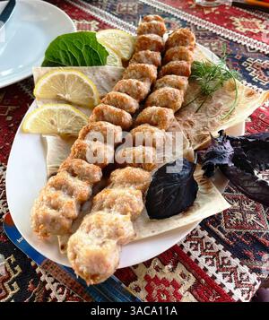 Köstlicher armenischer Kebab aus Sevan-Flusskrebsen (Khorovats), serviert auf Lavash mit frischen Kräutern und Zitrone. Armenische Küche. Stockfoto