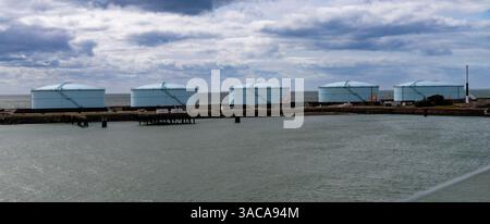 Le Havre, Frankreich-3. April 2024, fünf große zylindrische Öllagertanks mit Außentreppen stehen in einer Reihe am Küstenterminal nahe ruhiger Lage Stockfoto